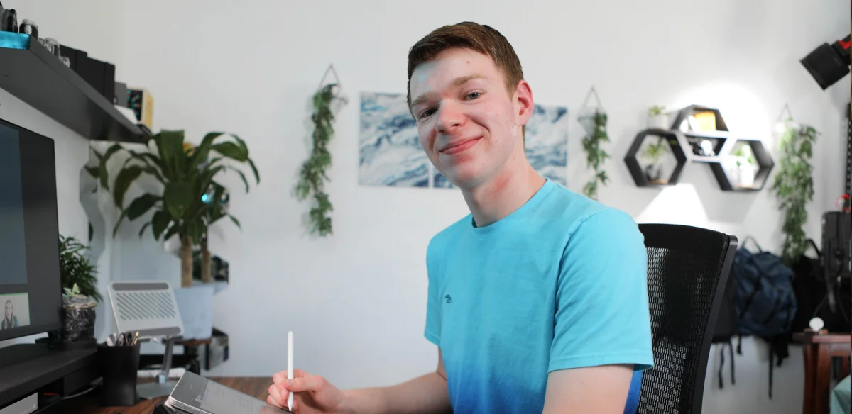 High school student wearing a light blue shirt and taking notes at home
